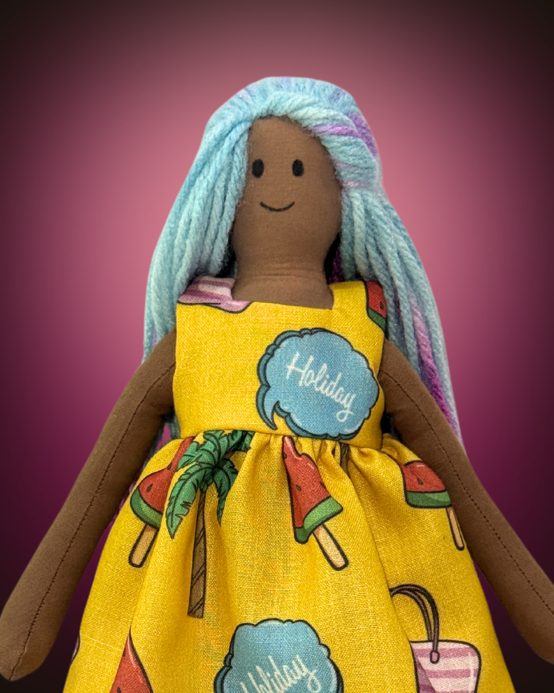 Handmade dark-skinned rag doll with blue yarn hair, wearing a bright yellow holiday-themed dress with ice cream and sunglasses print.