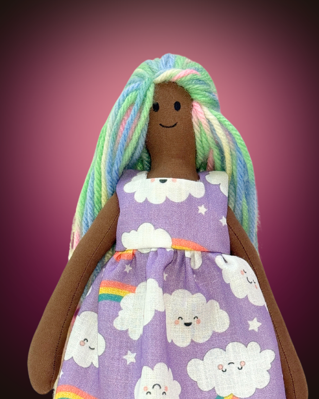 Eco-friendly baby doll (UNINA ESPRESSO RAINBOW) adorned with a whimsical purple clouds dress, made from natural materials