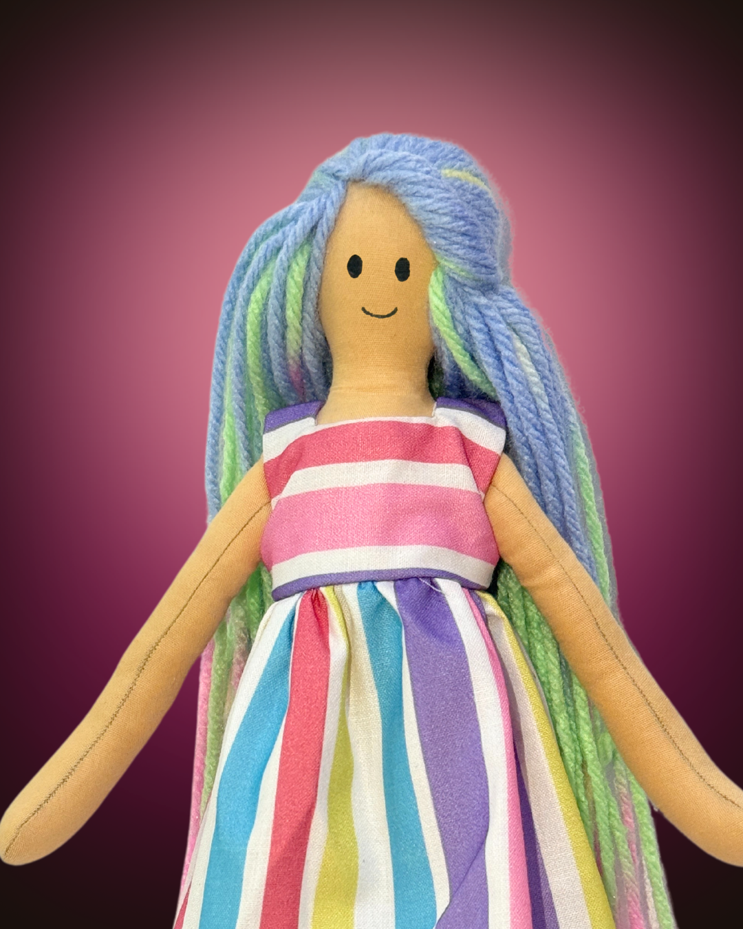 Eco-friendly soft doll with sky blue and green yarn hair, wearing a vertical rainbow-striped dress, safe and plastic-free for kids