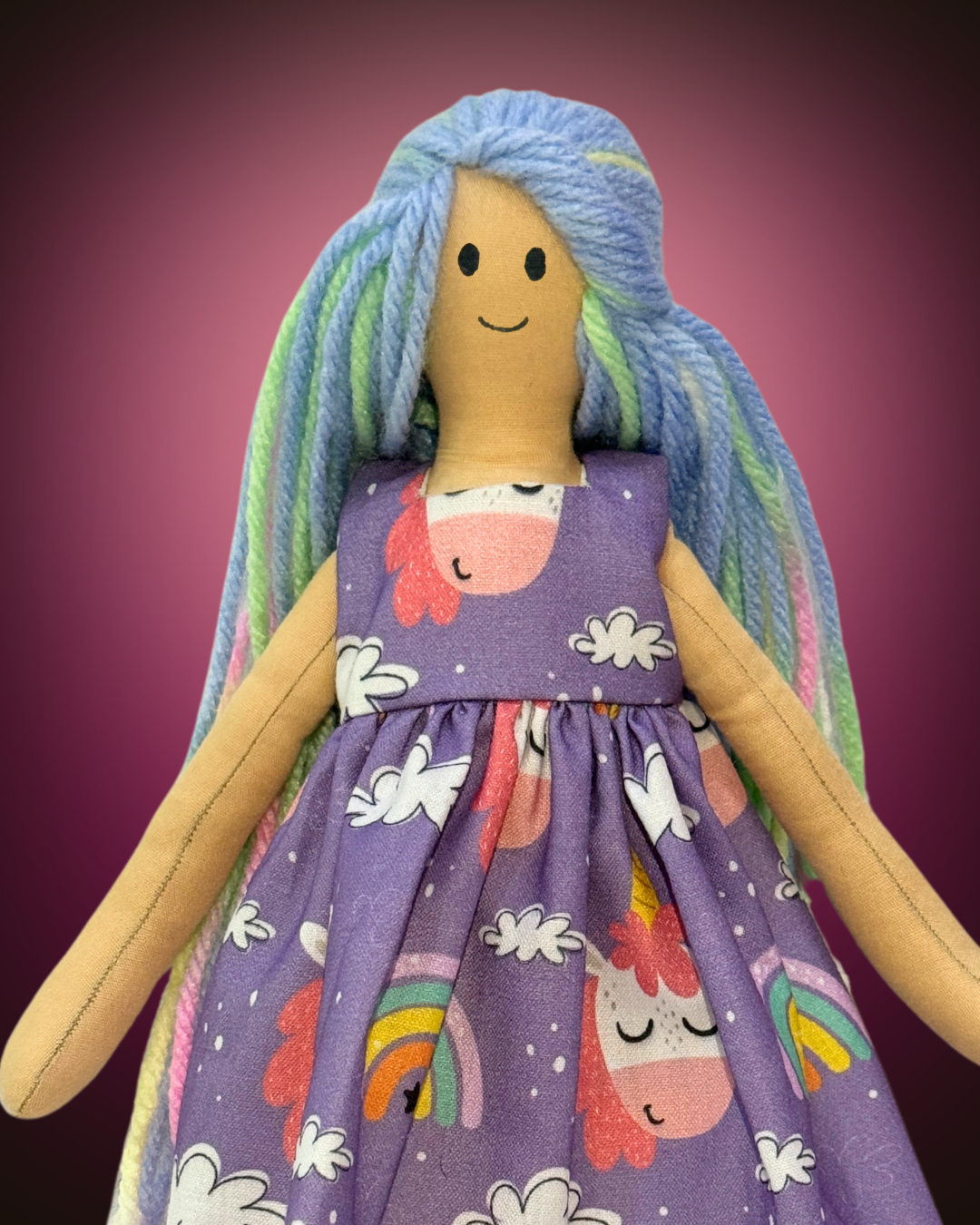 Handcrafted rag doll with multicolored yarn hair, dressed in a purple dress with unicorns and rainbows, perfect for imaginative play.
