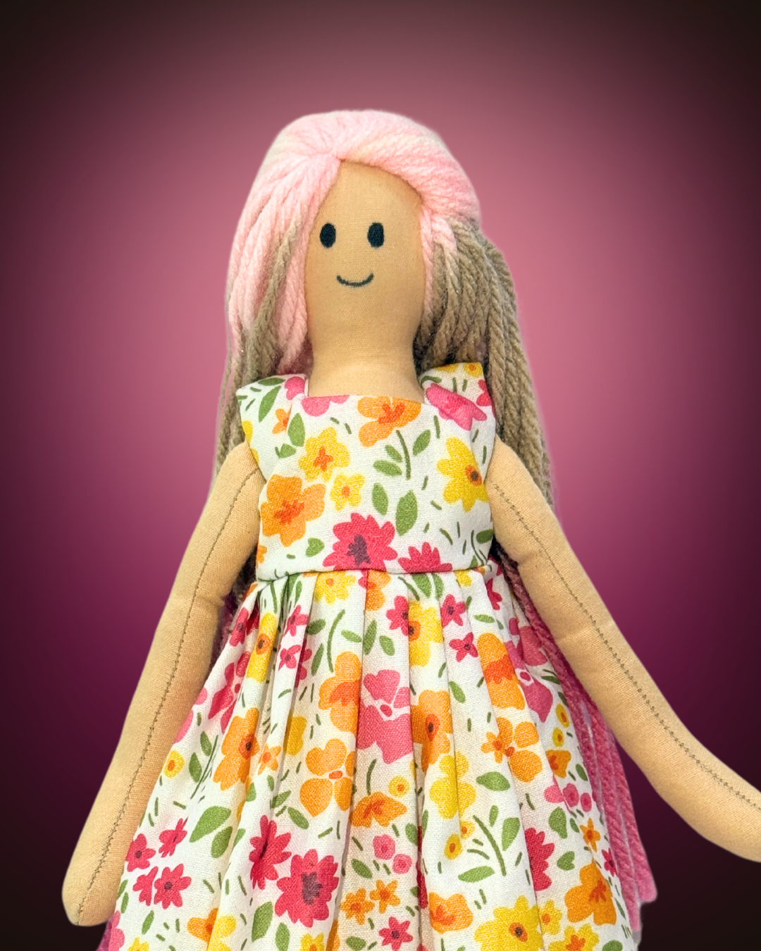 Light-skinned rag doll with soft pink and cream yarn hair, wearing a floral dress, ideal as a soft, plastic-free companion for baby girls